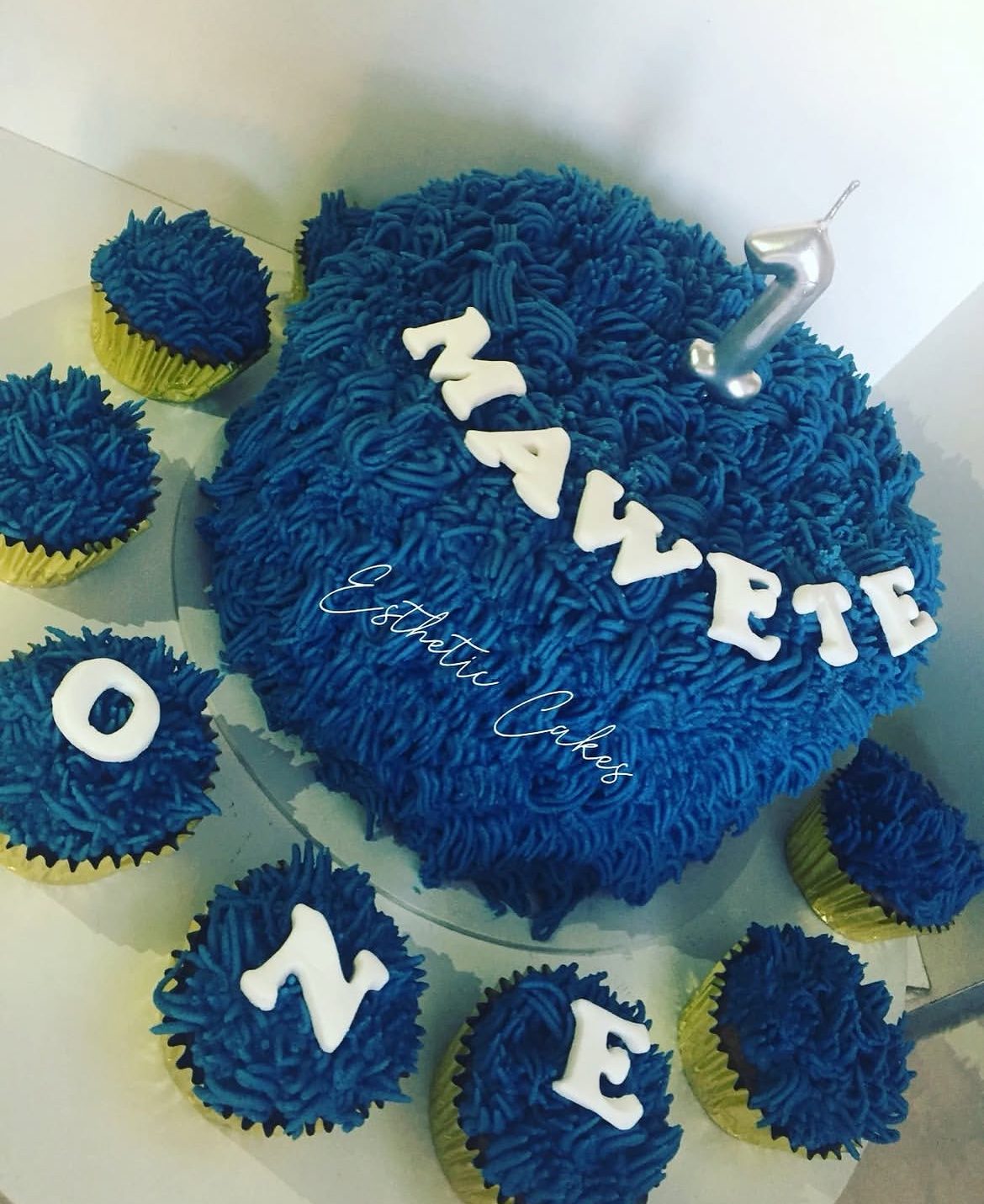 Blue textured first birthday cake reading 'Maweti One'