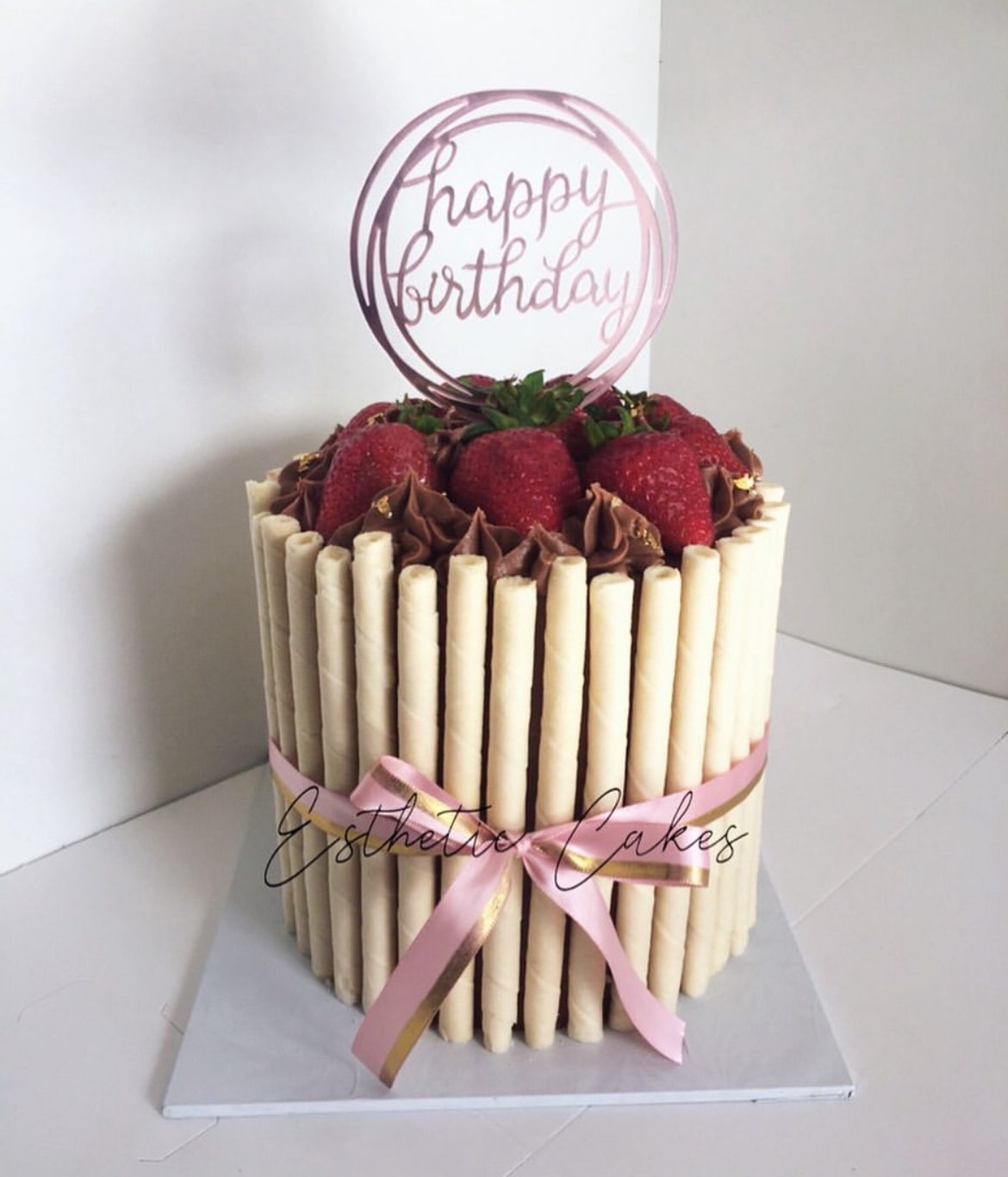 Buttercream cake ringed with pink chocolate stick decorations