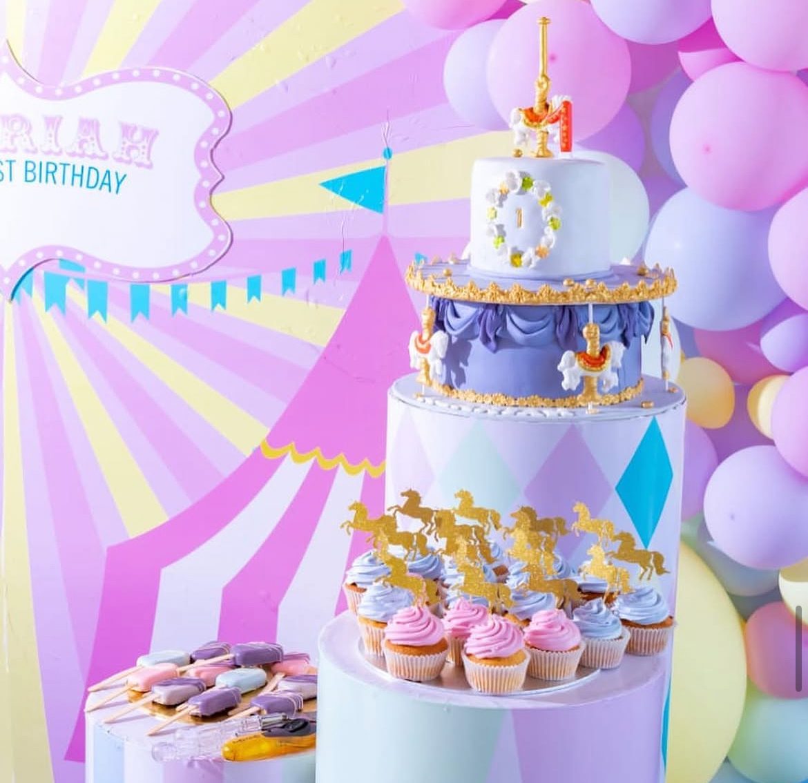 First birthday cake styled with rainbow party backdrop