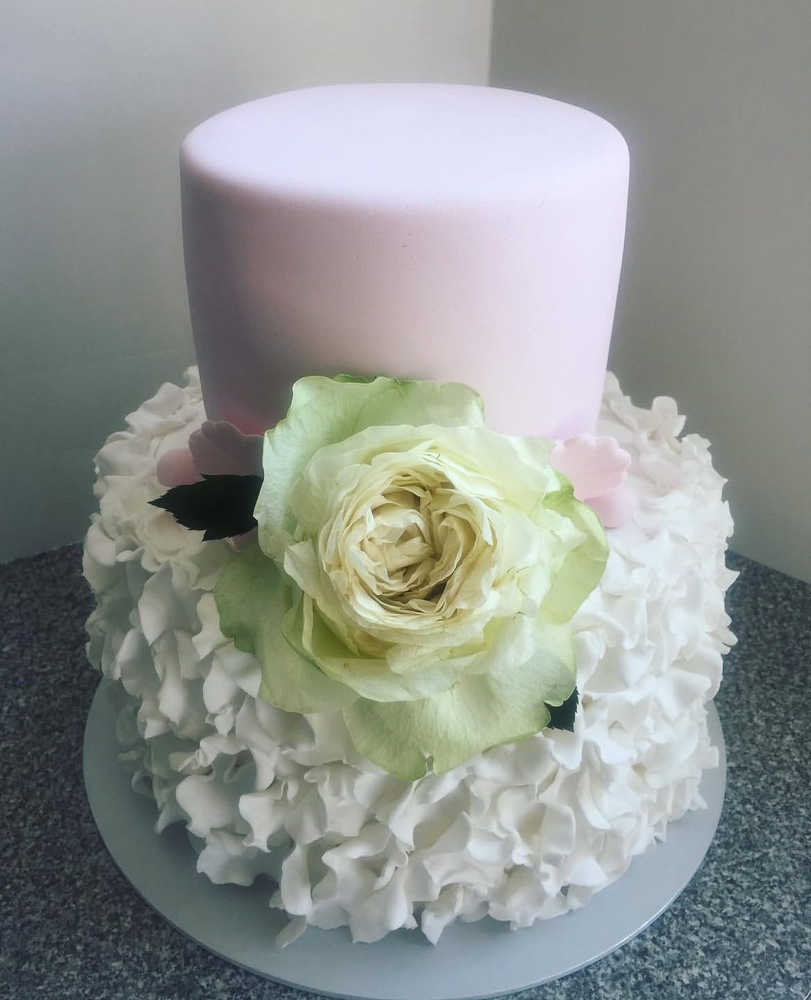 Two-tier white wedding cake with fresh white roses