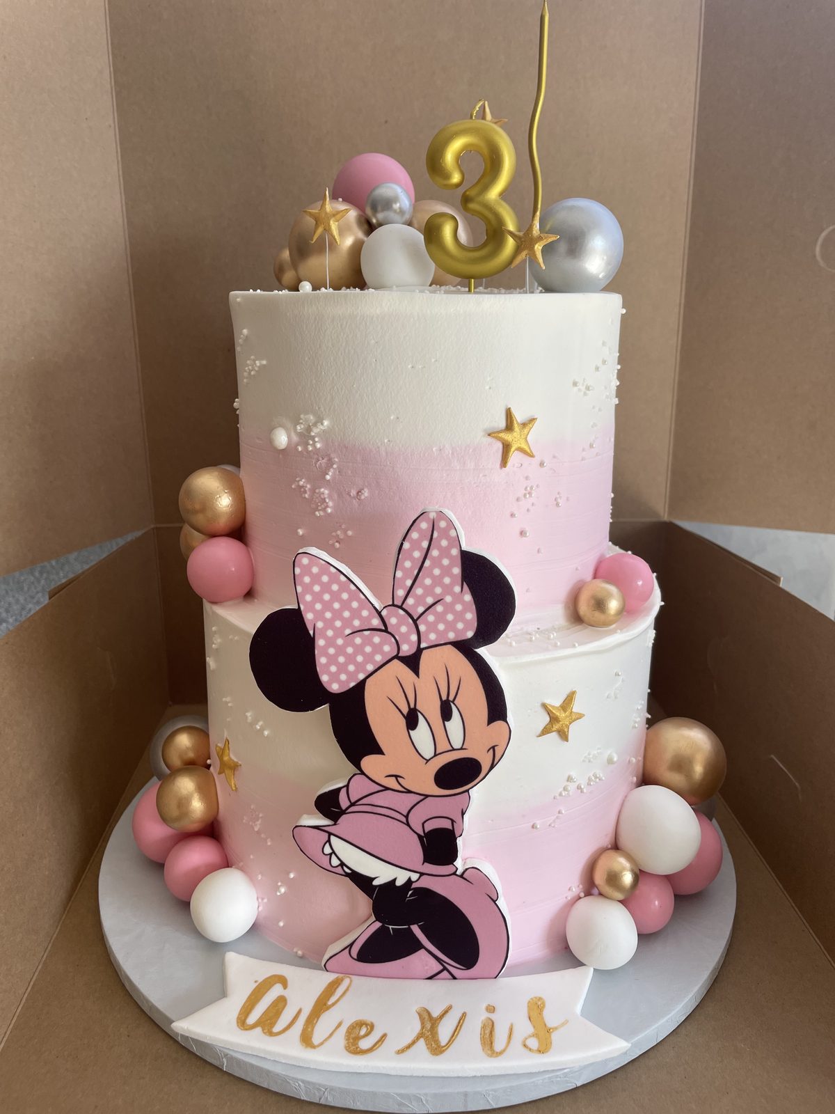 Two-tier Minnie Mouse 3rd birthday cake with pink and cream detail