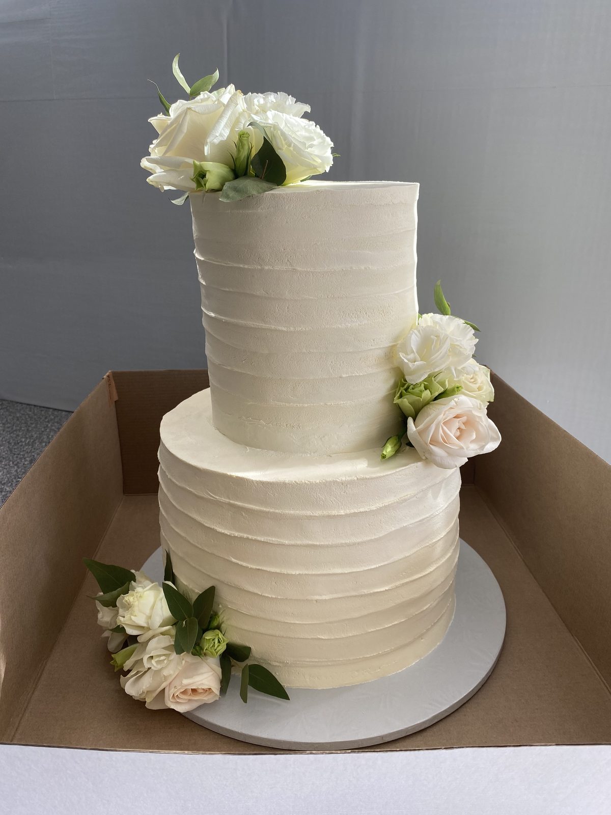 Two-tier white textured wedding cake with fresh flowers