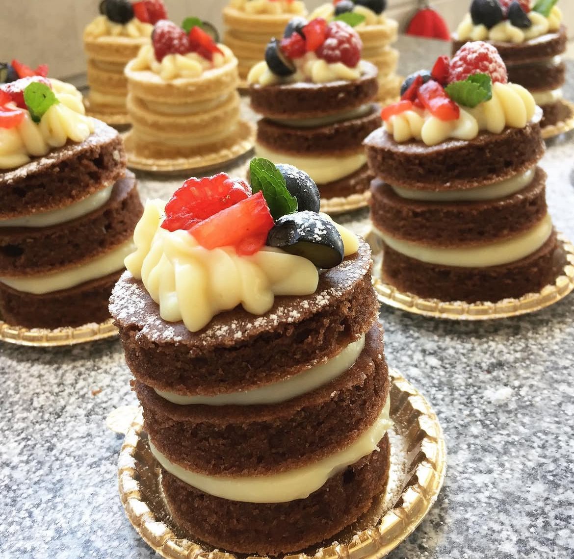 Individual mini cakes topped with fresh strawberries and cream
