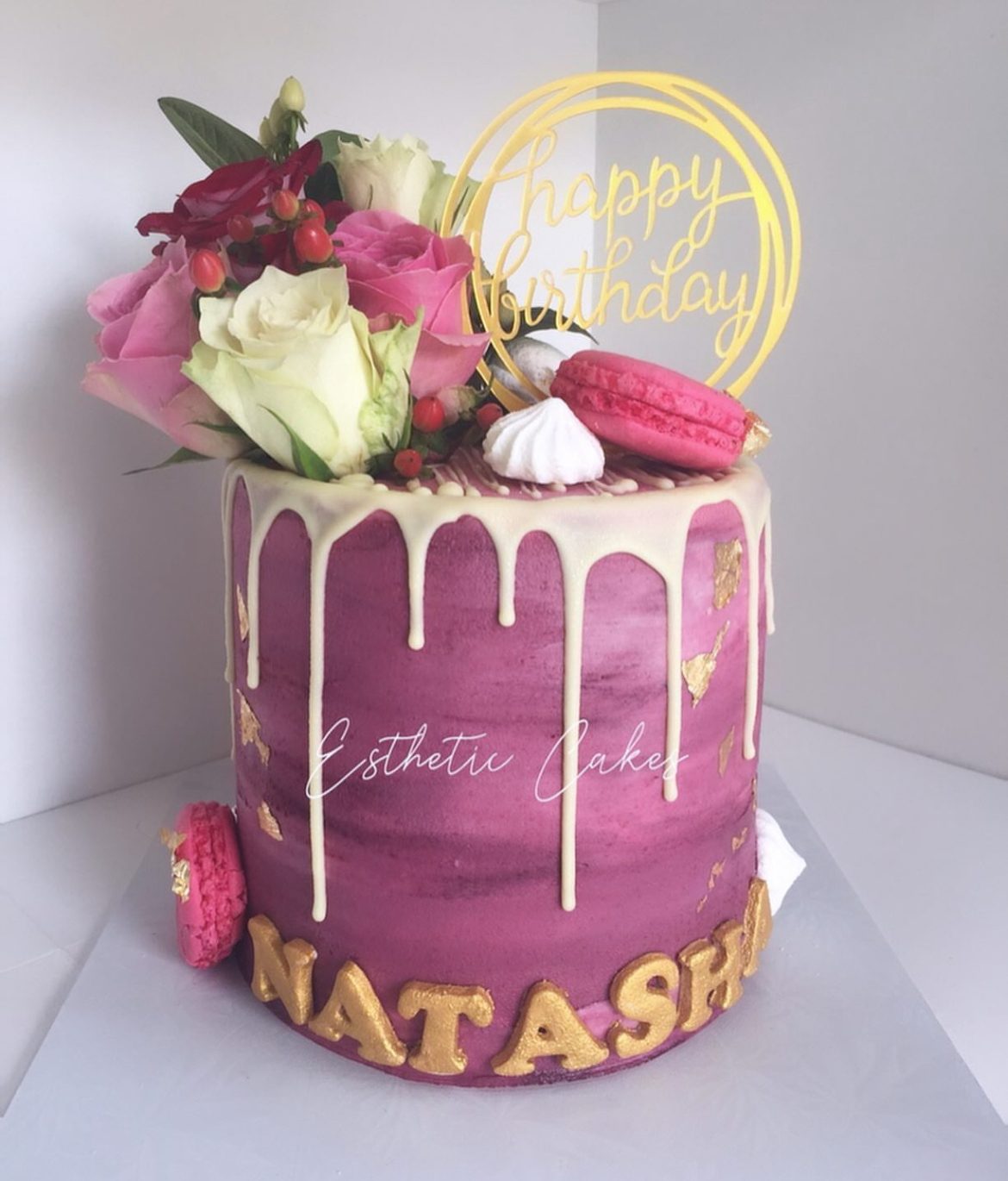 Pink birthday cake with fresh flowers and gold happy birthday topper