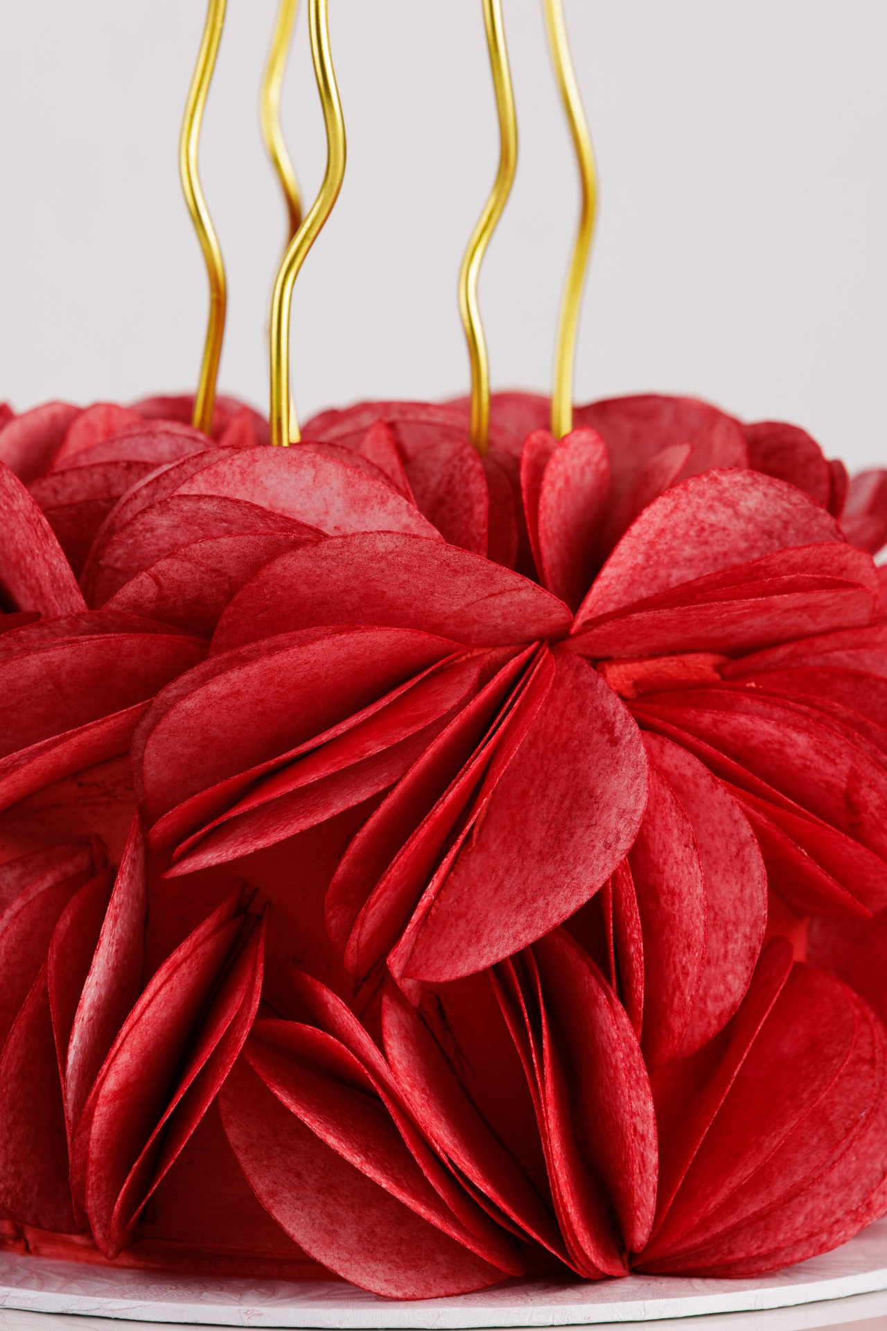 Deep red petal-textured celebration cake with gold wavy candles