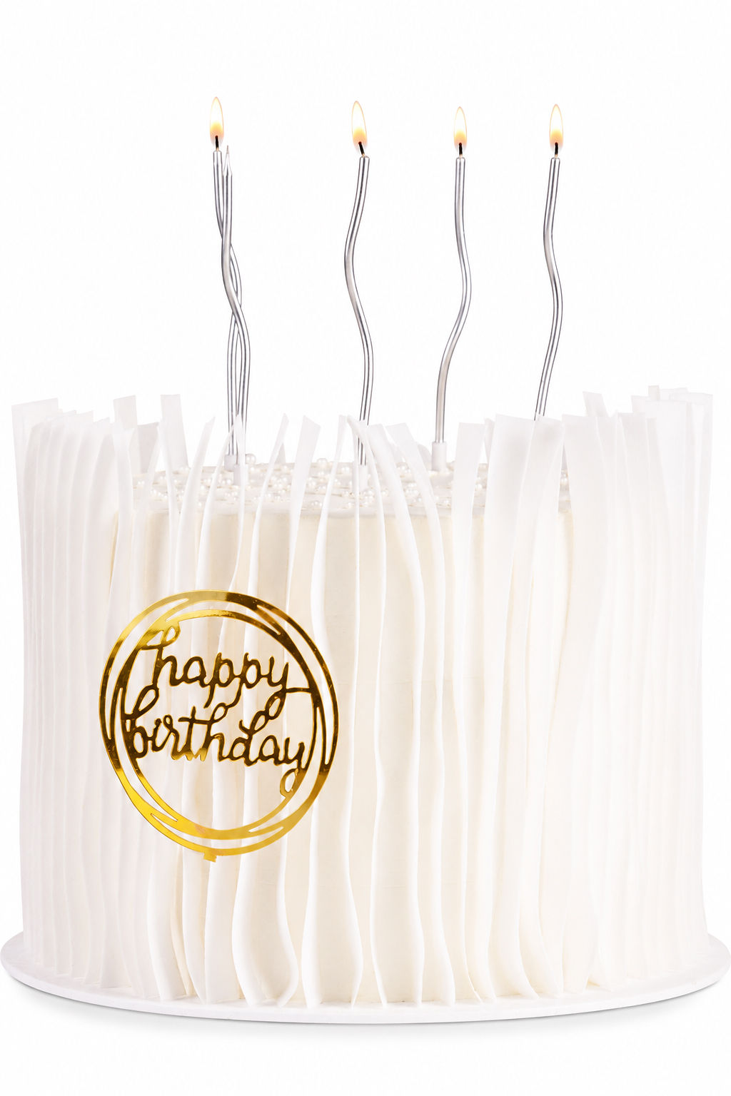White ribbon-textured cake with gold happy birthday topper and slim silver candles