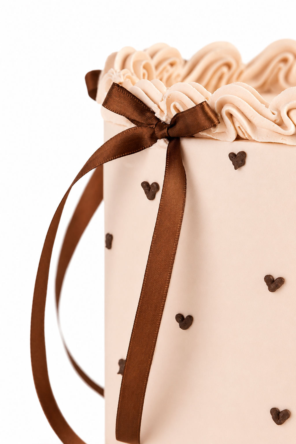 Blush cake with tiny chocolate hearts and a brown satin bow